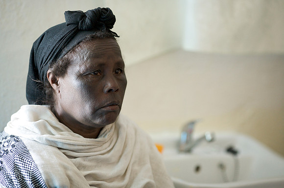 Tayech, age 50.  Tayech supports her two children selling candles by church.